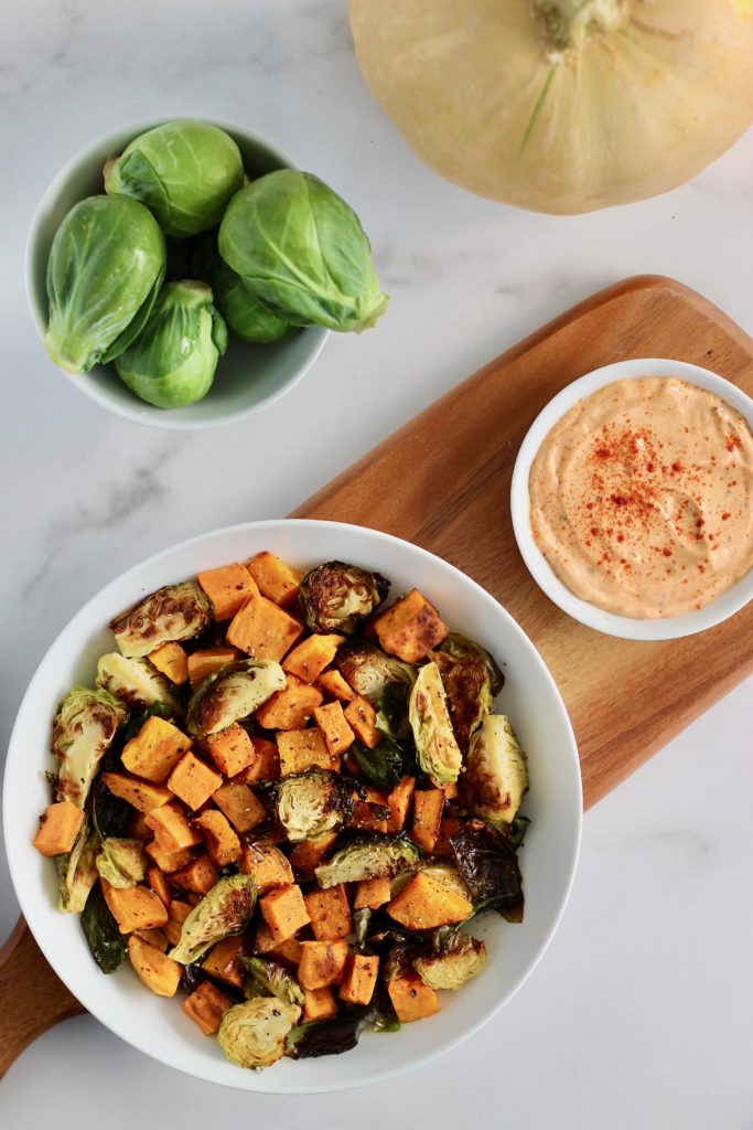 Looking for an easy side dish recipe using up all those delicious winter squash and Brussels sprouts? Try making Roasted Fall Vegetables served with Smoked Paprika Aioli sauce. It goes great alongside quinoa cakes, burgers, and salmon! #HolidaySide #Vegetarian #FallVegetables #Brussels #Squash #EasyRecipes
