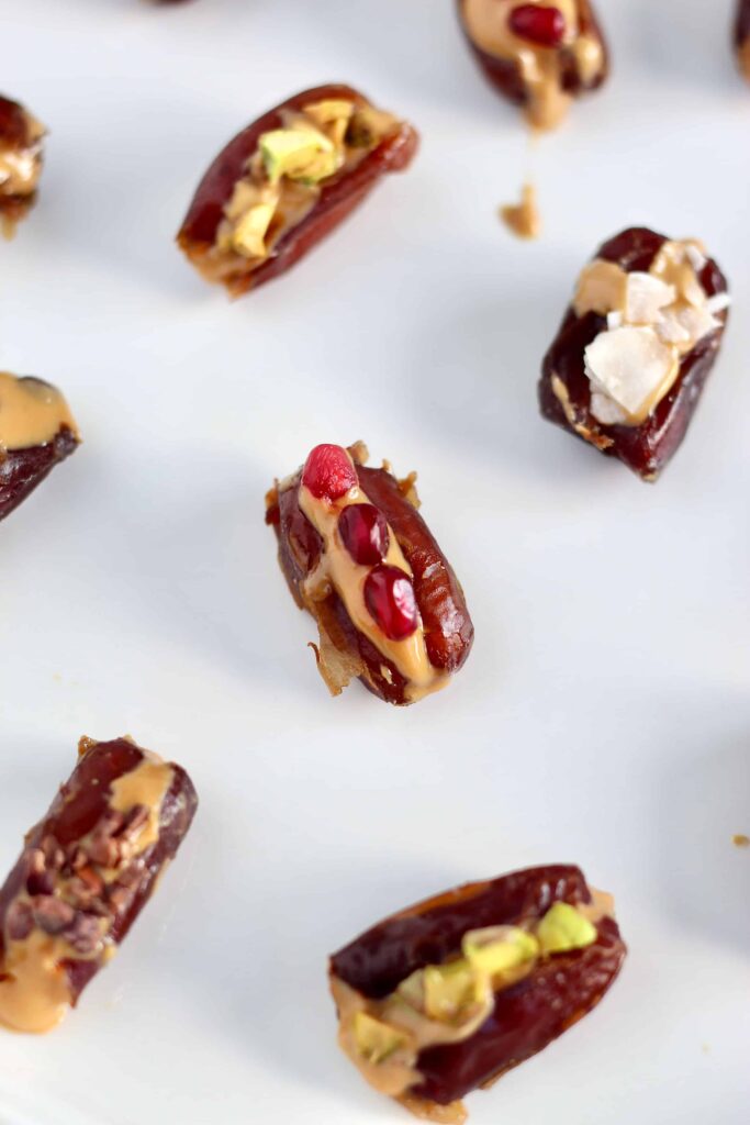 Looking for a sweet snack that comes together in less than 5 minutes? Try these healthy vegan stuffed dates filled with any nut butter and toppings of your choice. Perfect for an energizing snack or party appetizer. #HealthySnack #StuffedDates #Vegan #3Ingredients