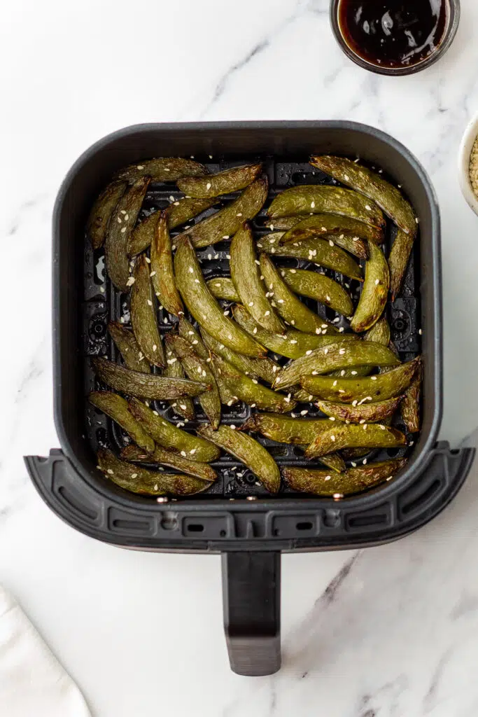 Air-fried sugar snap peas with sesame seeds in an air fryer basket