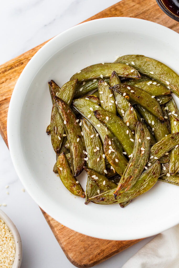 Crispy snap peas with sesame seeds in a simple white serving bowl