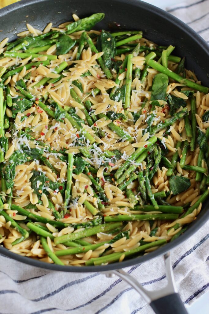 Close up of cooked asparagus and spinach over orzo