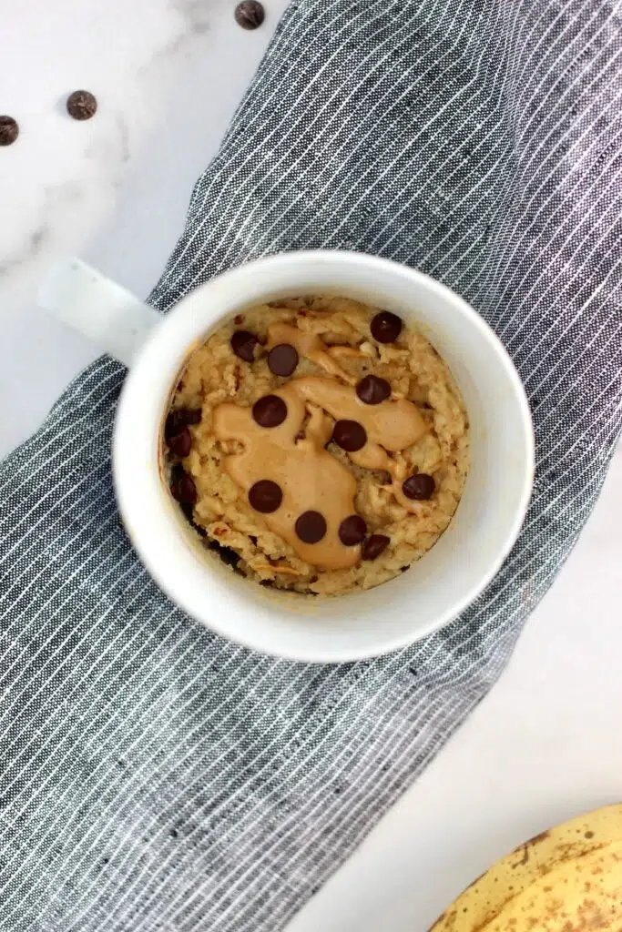 Mug cake drizzled with peanut butter and topped with sugar-free chocolate chips