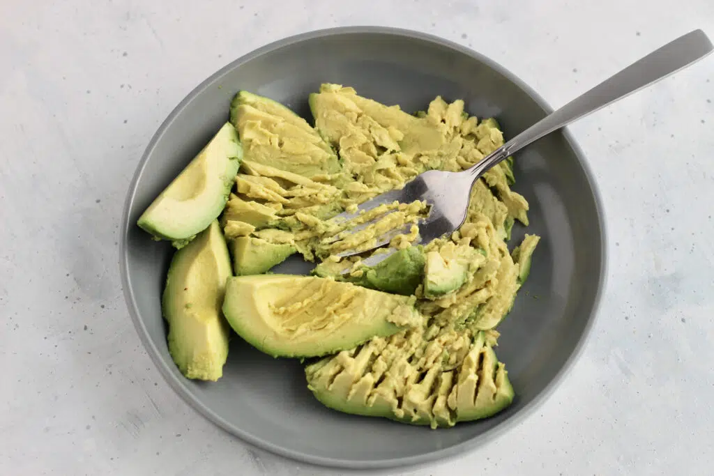 Mashing avocado in a grey bowl