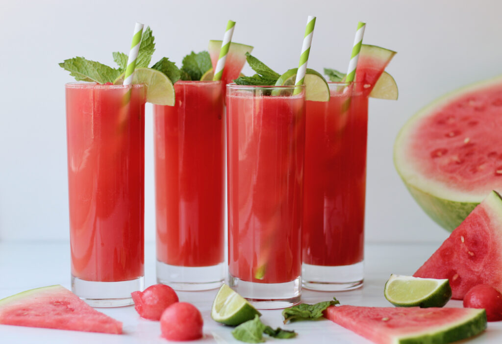 Four glasses of watermelon mocktails surrounded by watermelon slices