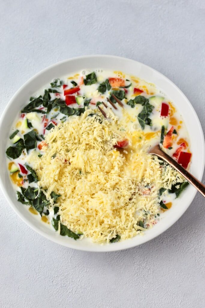 Mixing eggs, cheese, and veggies