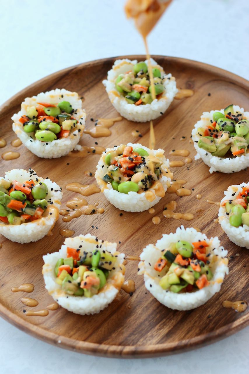 Sushi cups on wooden tray with spicy mayo drizzled over