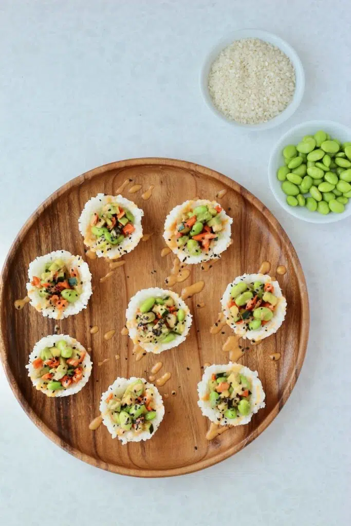 Sushi cups on wooden tray with edamame
