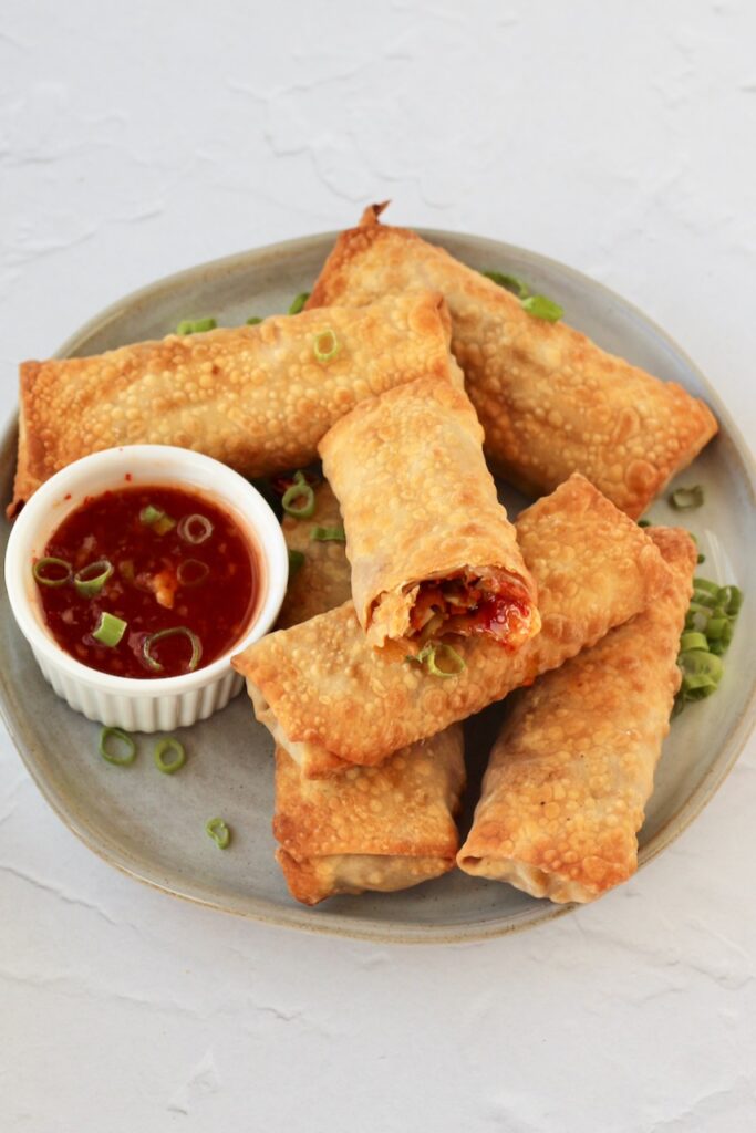 Air fryer egg rolls served on wood platter with sauce