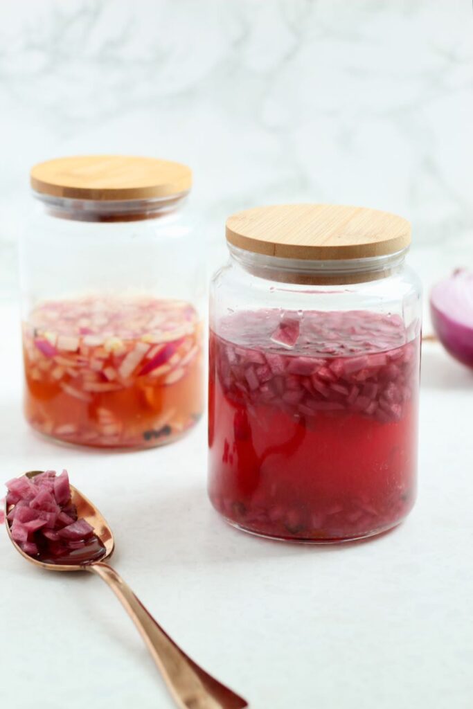 Homemade quick pickled red onions in a glass jar with tan lid