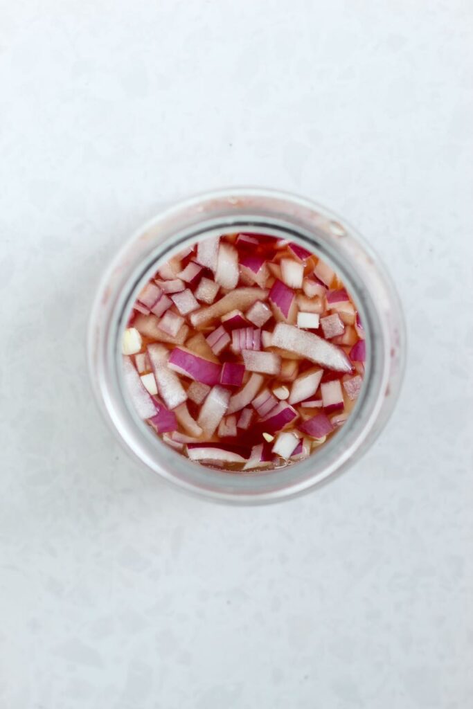Diced red onions in jar covered in brine