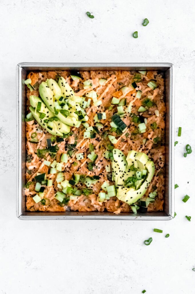 Sheet pan sushi bake sprinkled with sesame and chopped greens.