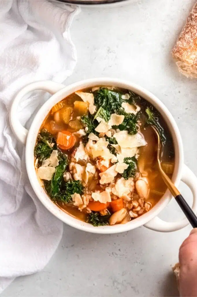 Hearty vegetable and farro stew garnished with cheese flakes, perfect for a cozy meal.