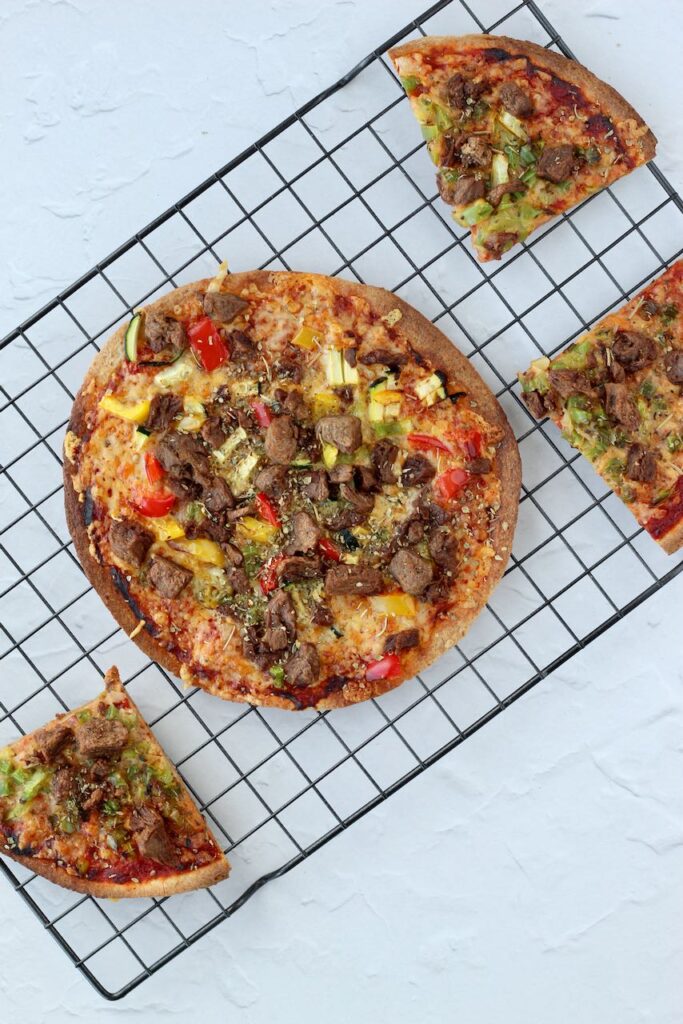 Air-fried tortilla pizza with steak tips and cheese on cooling rack