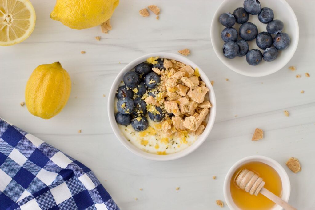 Lemon Blueberry Protein Yogurt Bowl with fresh blueberries and crunchy graham topping and honey