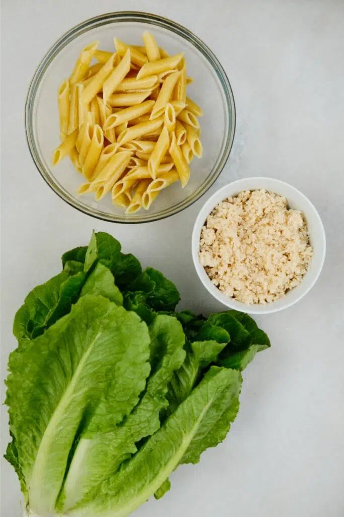 Cooked pasta, cooked quinoa, and lettuce next to each other. 