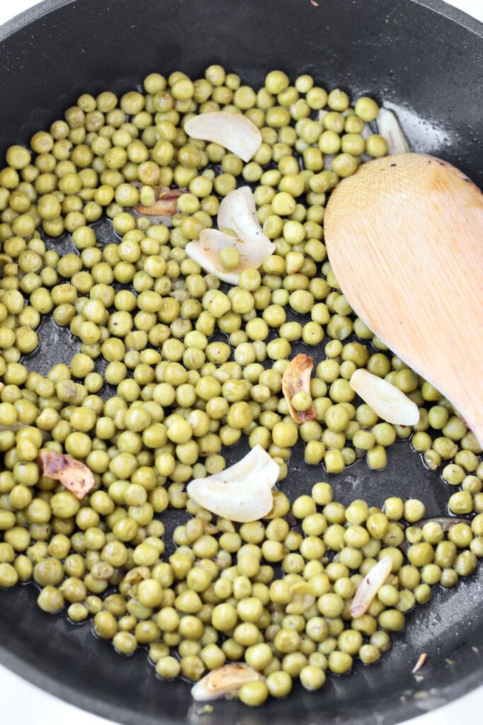 Peas cooking in pan with garlic