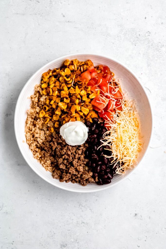 quinoa, ground beef, corn, tomatoes, black beans, cheese, and greek yogurt on plate