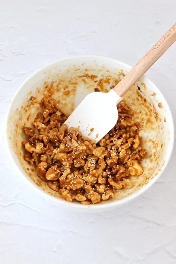 Glazed walnuts in a small white bowl before baking