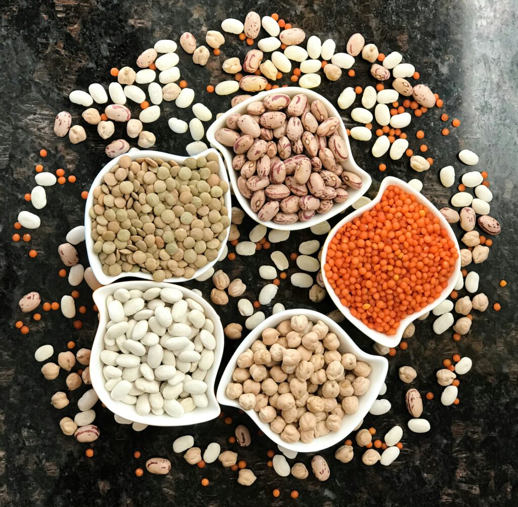 Five different kinds of legumes in white bowls