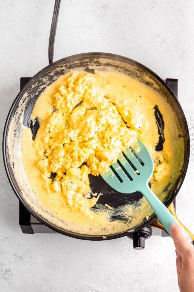 Cottage cheese eggs being stirred in skillet with spatula 