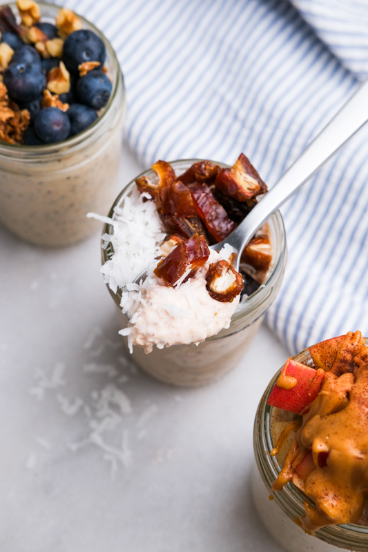 Taking a spoonful of medjool dates and coconut flakes on top of the overnight oats