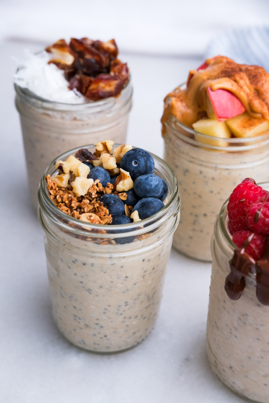 Close up of four mason jars of blended overnight oats with different toppings