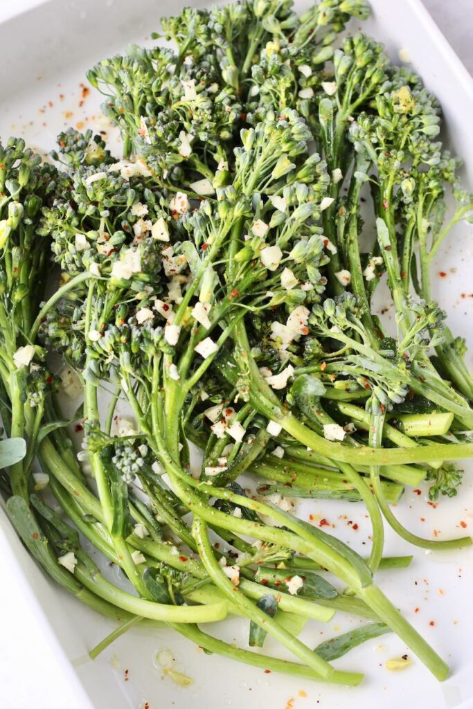 Seasoned broccolini with garlic and red pepper flakes before grilling
