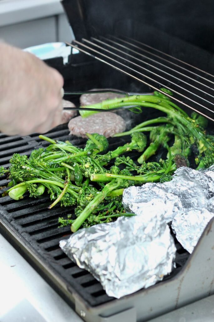 Foil packet on the grill next to broccolini