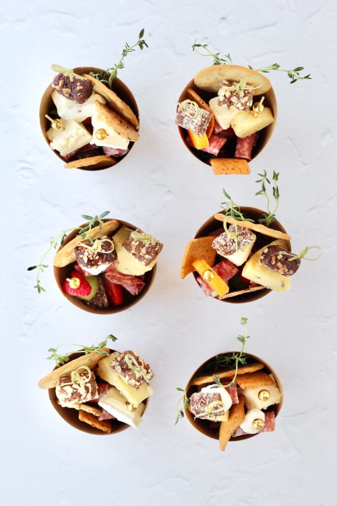 Six individual charcuterie cups with skewers of ingredients