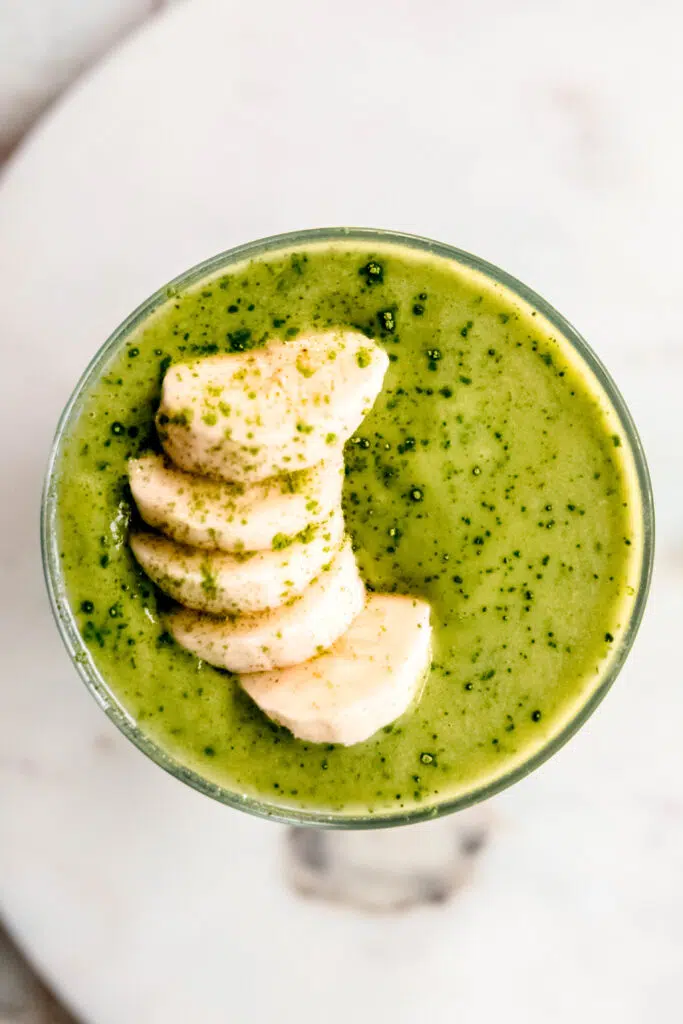 Birds eye view of green smoothie with banana slices on top.