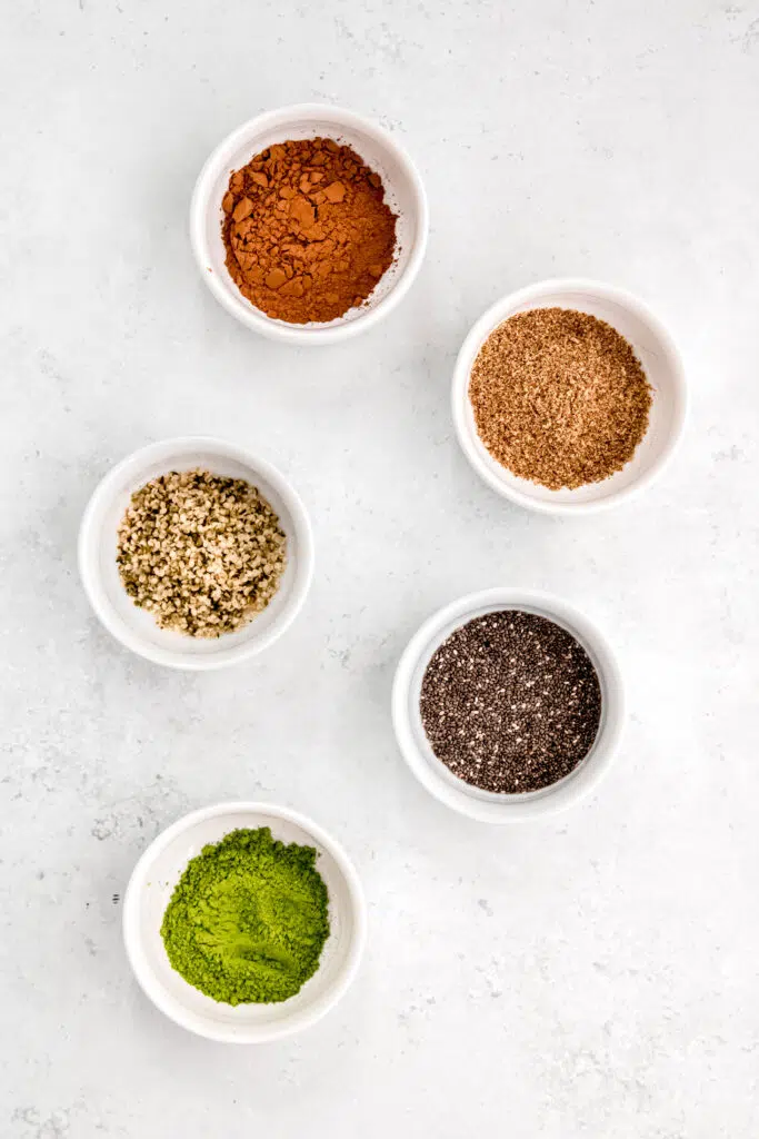 Add in's like cocoa, flaxseed, hemp seed, chia seed, and matcha in white bowls.