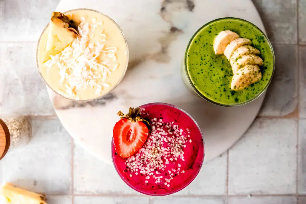 Birds eye view of pink, green, and yellow smoothies.