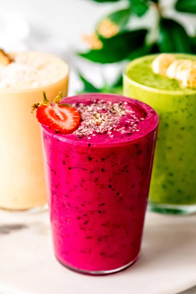 Pink, green, and yellow smoothies next to each other.