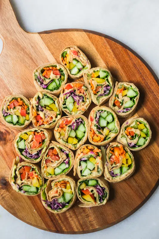 Final colorful veggie pinwheels laid out on wooden serving board