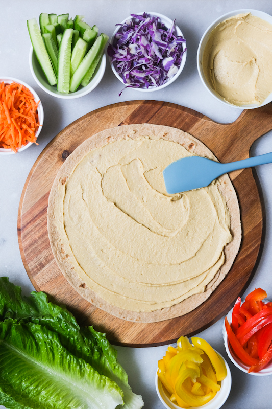 Hummus being spread onto whole wheat tortilla