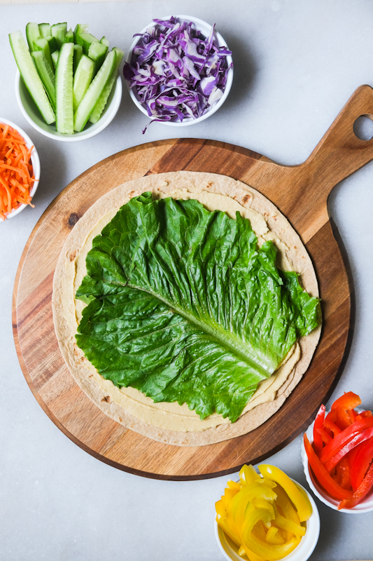 Large piece of romaine lettuce on top of hummus and tortilla