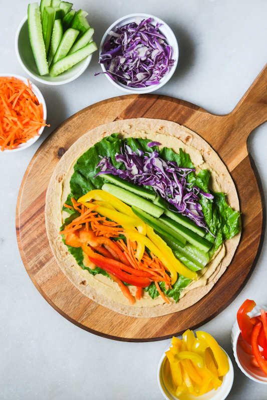 Sliced peppers, carrots, cucumbers, and cabbage arranged on lettuce