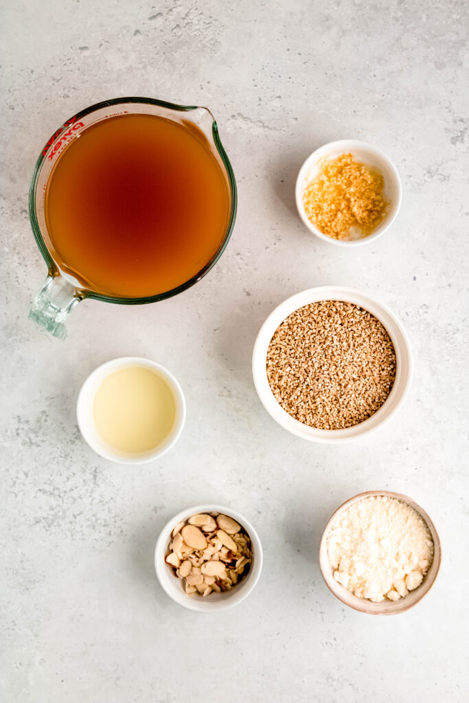 Ingredients to make savory oats: vegetable broth, minced garlic, dry oats, parmesan cheese, truffle oil, and nuts,