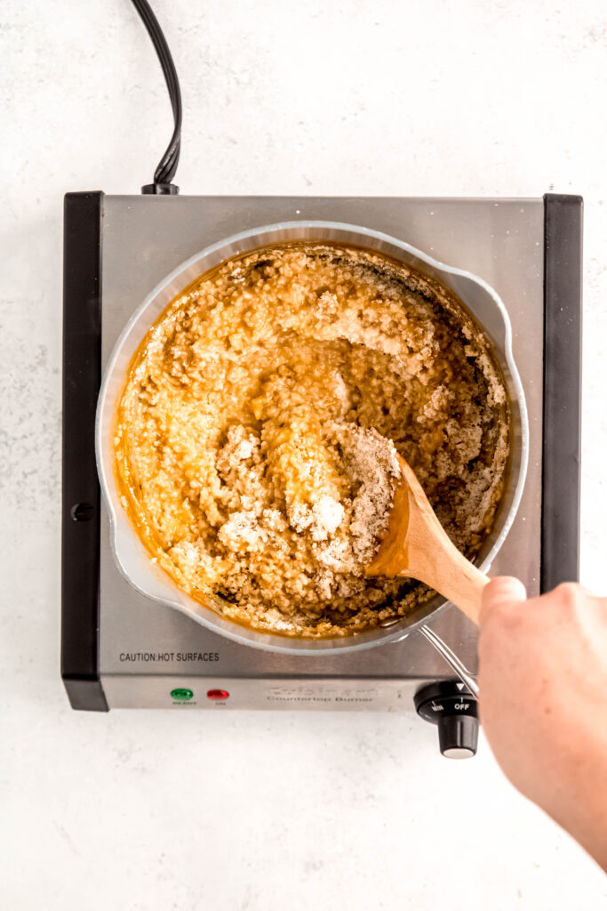 Mixing seasoning into cooked oats on burner.