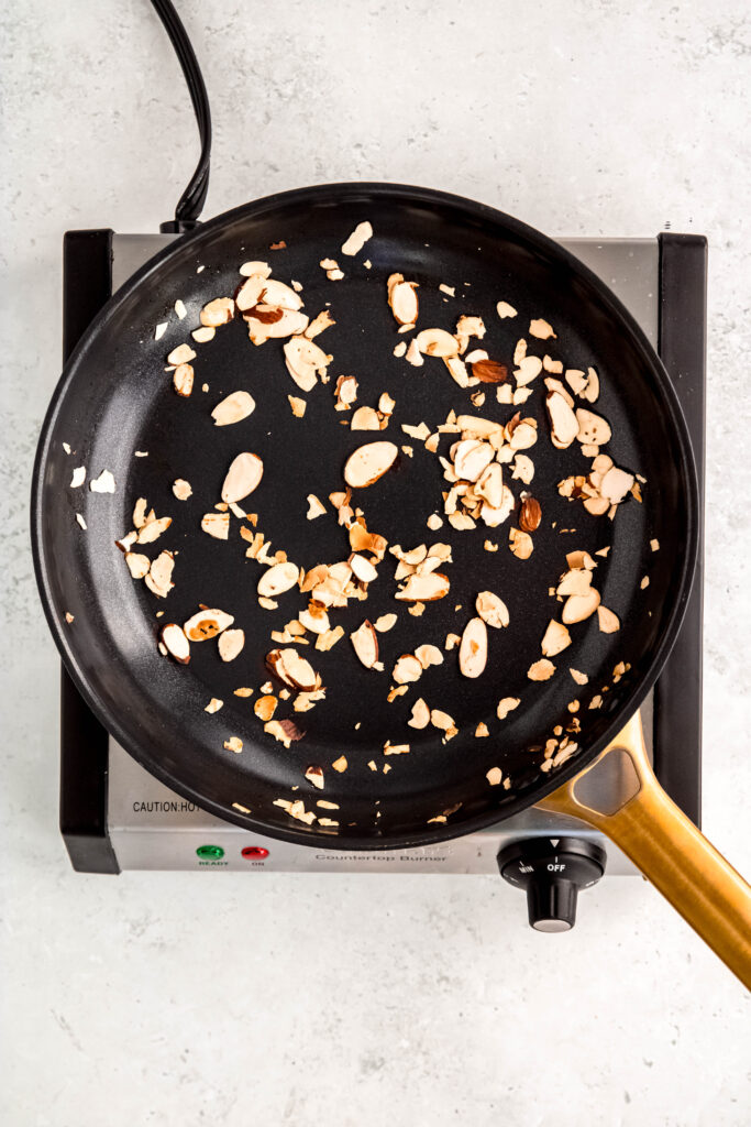 Almonds toasting in skillet on burner.