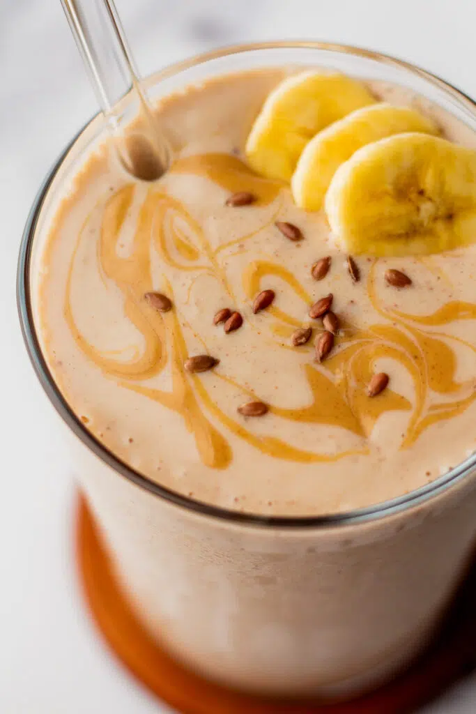 Close-up of a flaxseed smoothie with banana slices and flaxseeds on top.