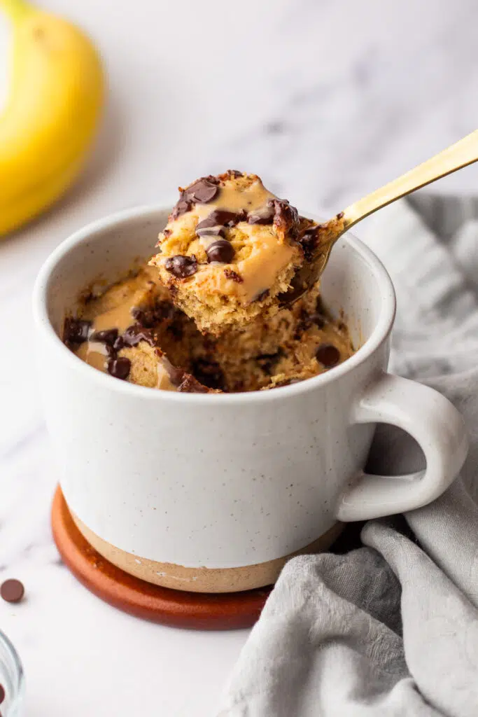 Lifting up spoonful of fluffy protein powder mug cake