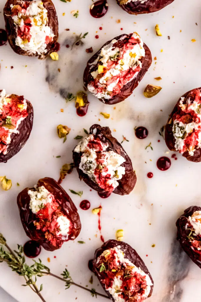 Multiple goat cheese stuffed dates on a platter with pistachios.