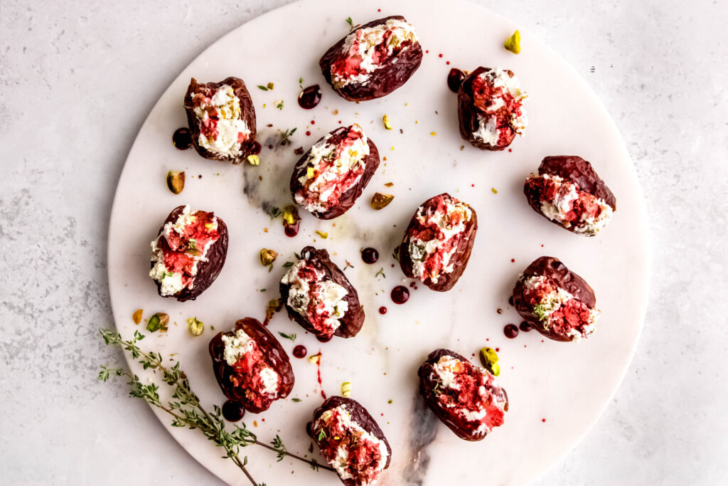 White platter with 12 goat cheese stuffed dates and fresh herbs.