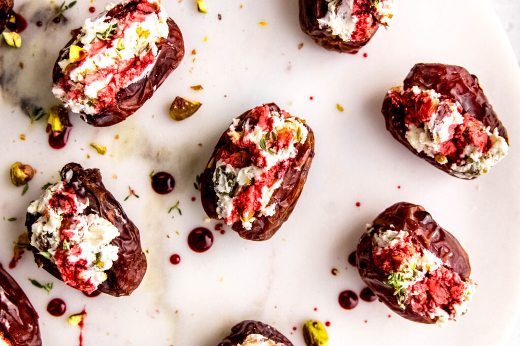 Over head view of goat cheese stuffed dates with pomegranate molasses drizzled about.