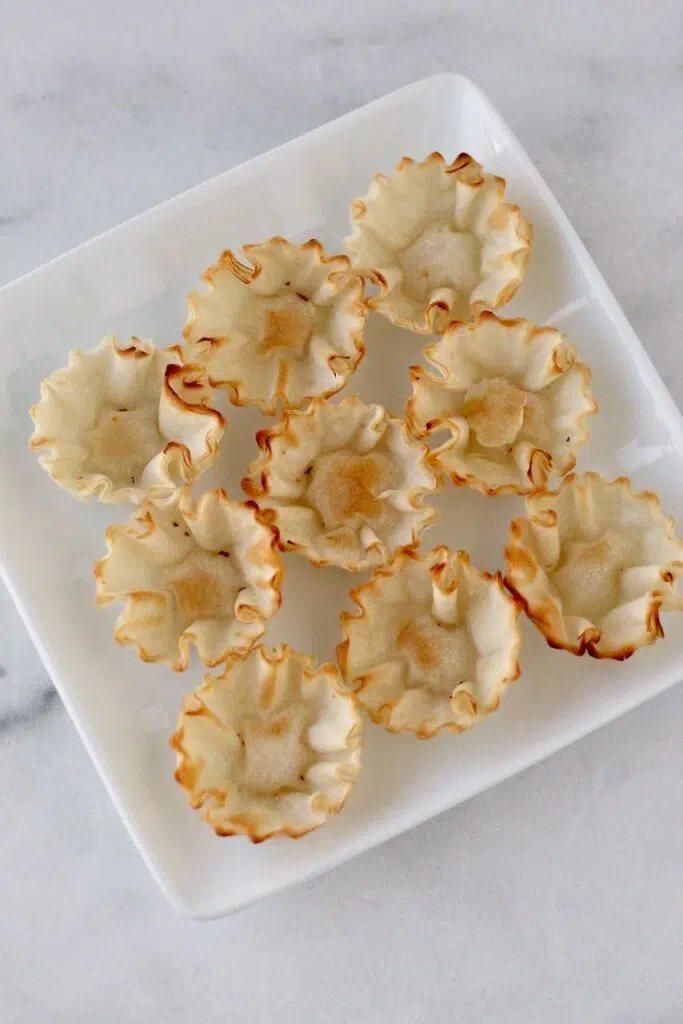 Nine empty phyllo shells on white plate