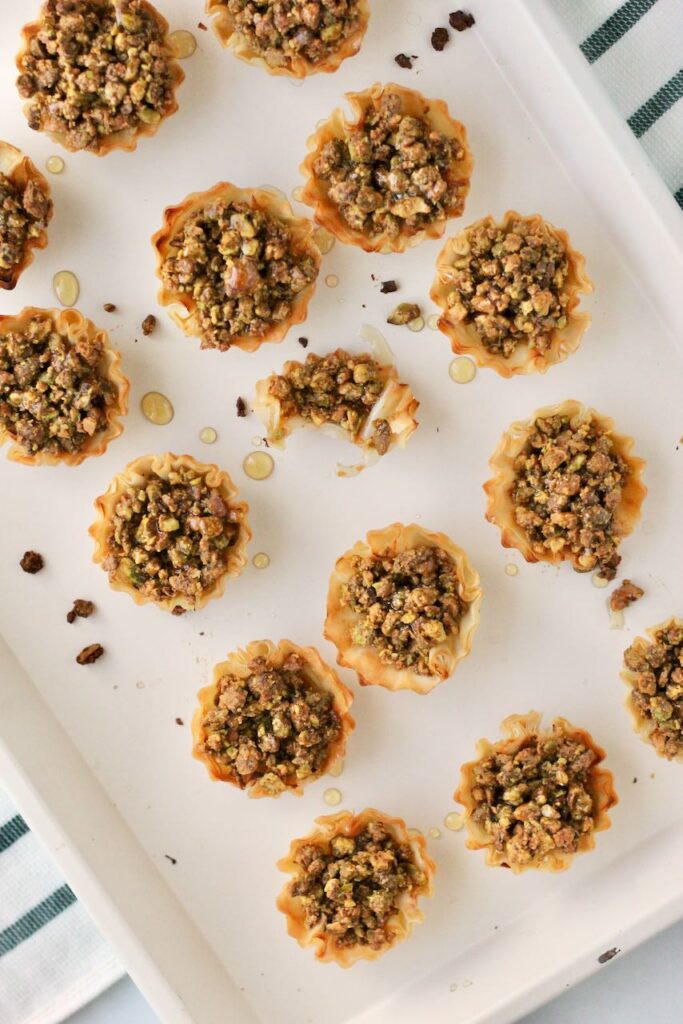 Finish baking sheet of pistachio baklava bites, one with a bite taken out.