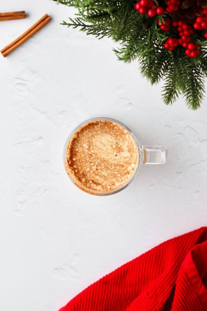 Cinnamon roll protein latte with pine tree branch in background