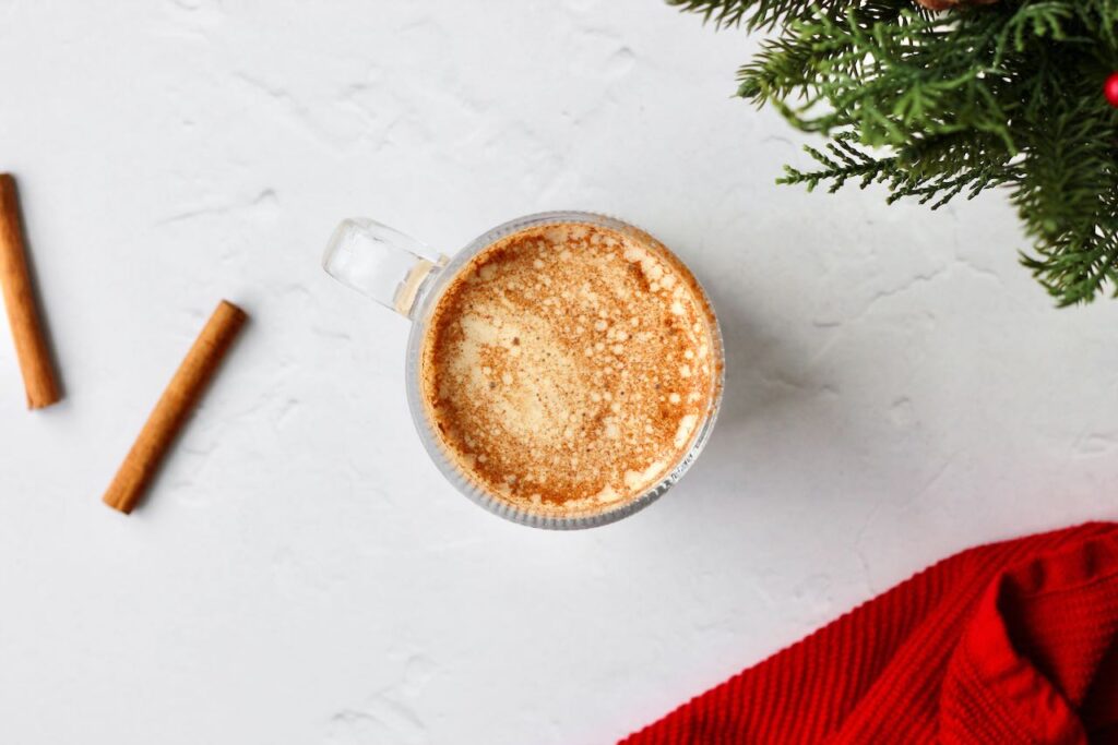 Cinnamon roll protein latte with cinnamon sticks and red towel 