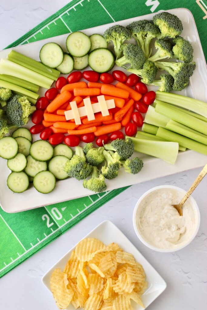 Veggie football platter next to chips and dip